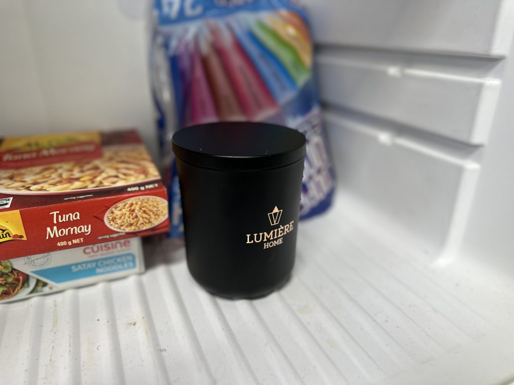 Black lumiere candle jar in the freezer with other freezer items